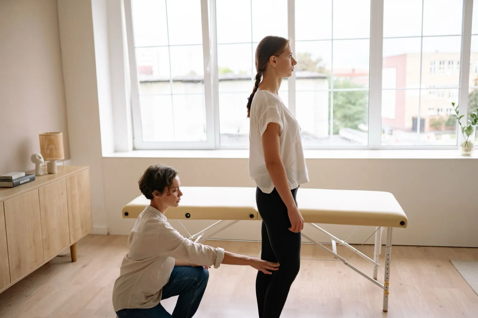 A physiotherapist assessing a standing client in a bright clinic room