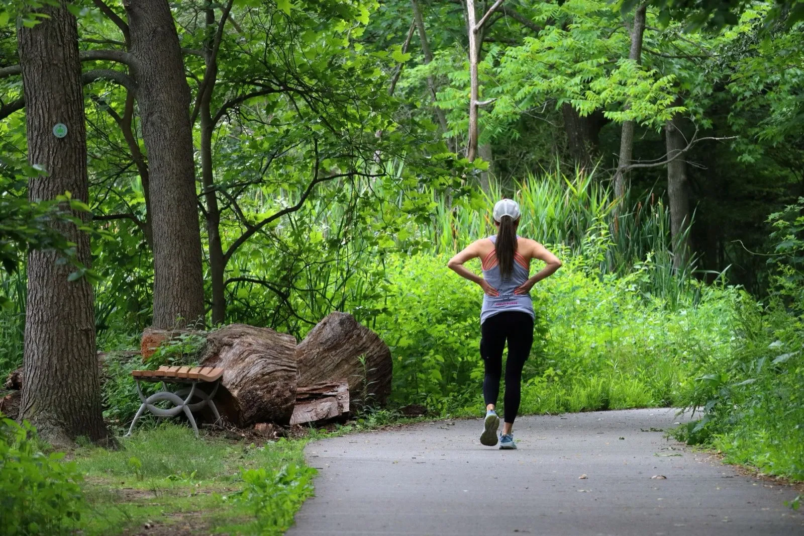 A woman running along a shaded path through a green park