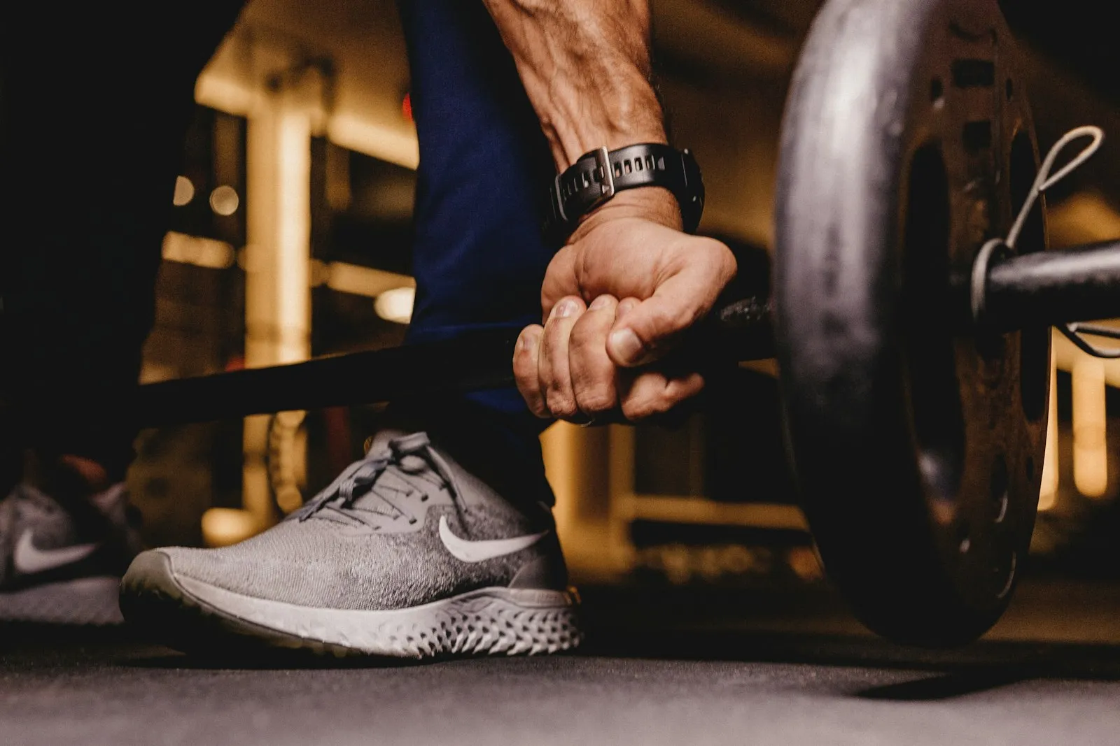 A person gripping a loaded barbell before a controlled lift