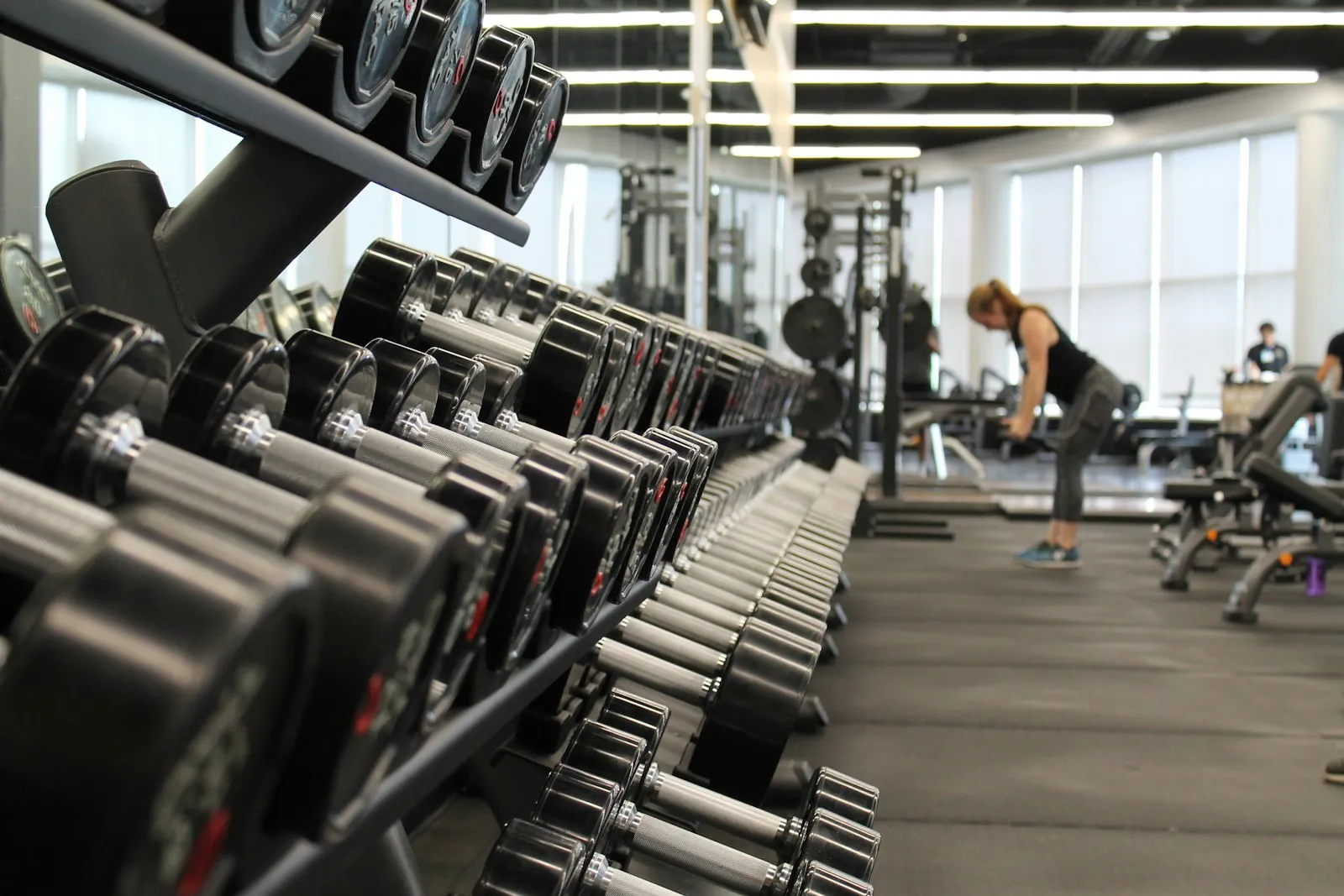 A dumbbell rack and someone training on a gym floor